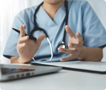 a doctor sitting at a desk with a laptop and a stethoscope.