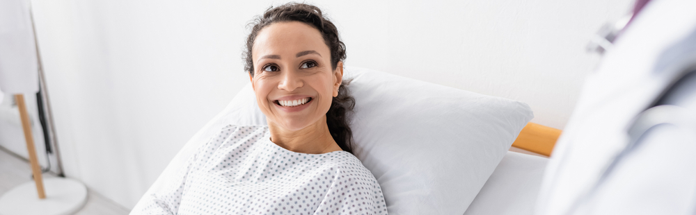 a woman laying in a hospital bed smiling.