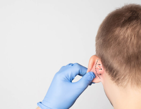 A young boy is getting an ear piercing.