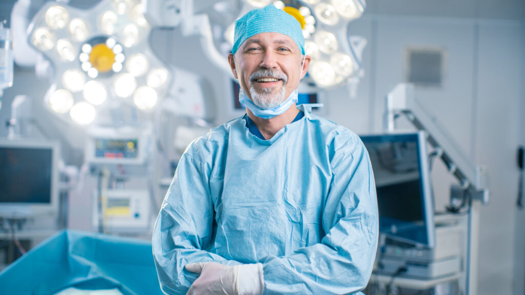 A smiling surgeon in an operating room.