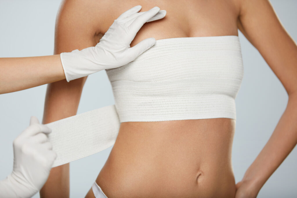 A woman is putting a bandage on her breasts.